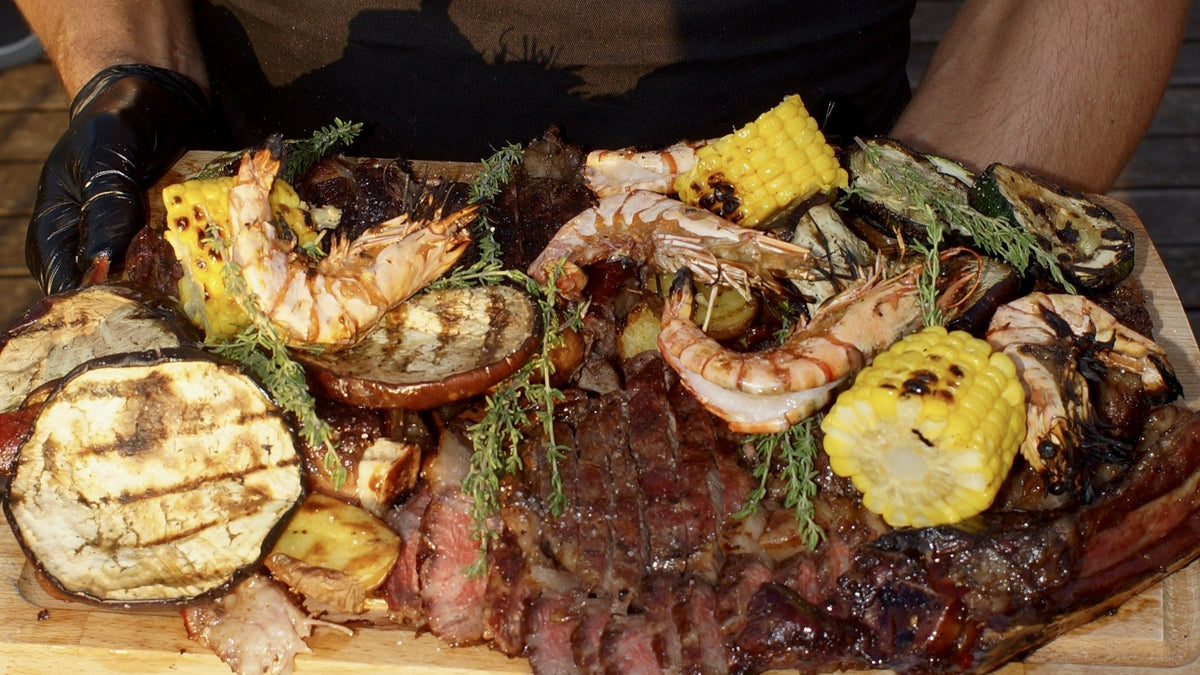 Bőséges kerti grill tál sült húsokkal, grillezett zöldségekkel és garnélával FELS BBQ kötényben tálalva